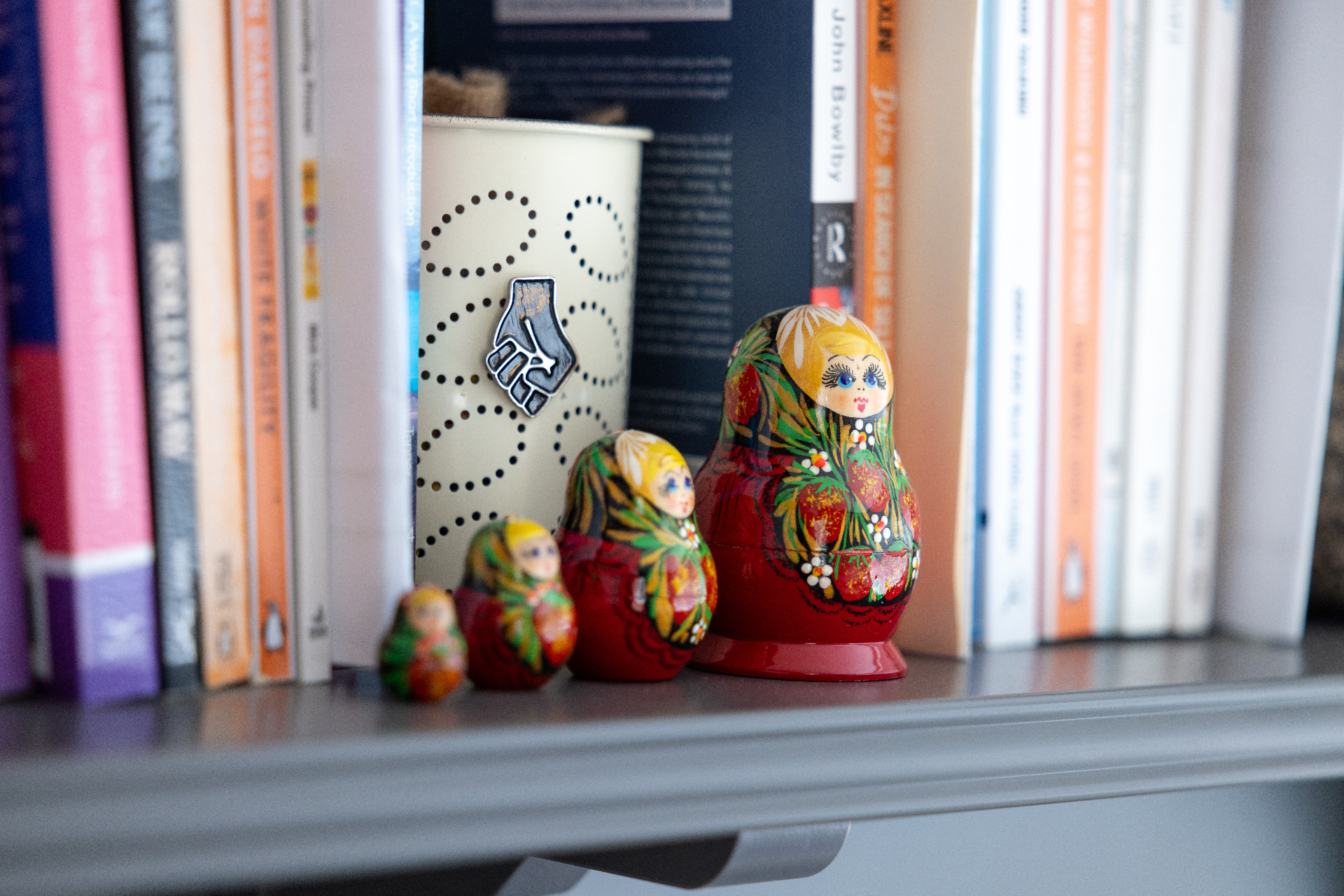 Hand-painted Russian nesting dolls beside a row of books in the therapy room